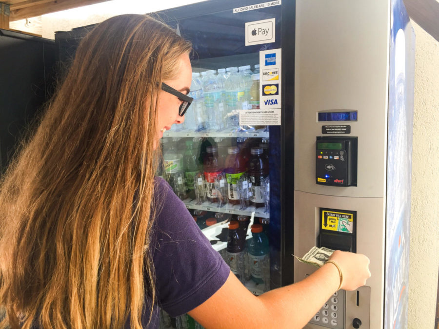 Freshman Ally Turner puts a dollar in the vending machine hoping to get a snack back.