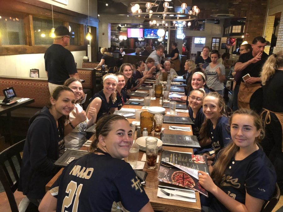 The softball team eats after completing their game.